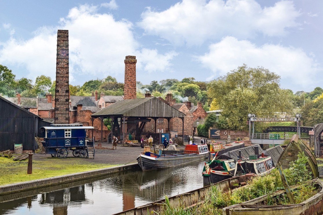 Canal with narrow boats in foreground, industrial chimneys behind